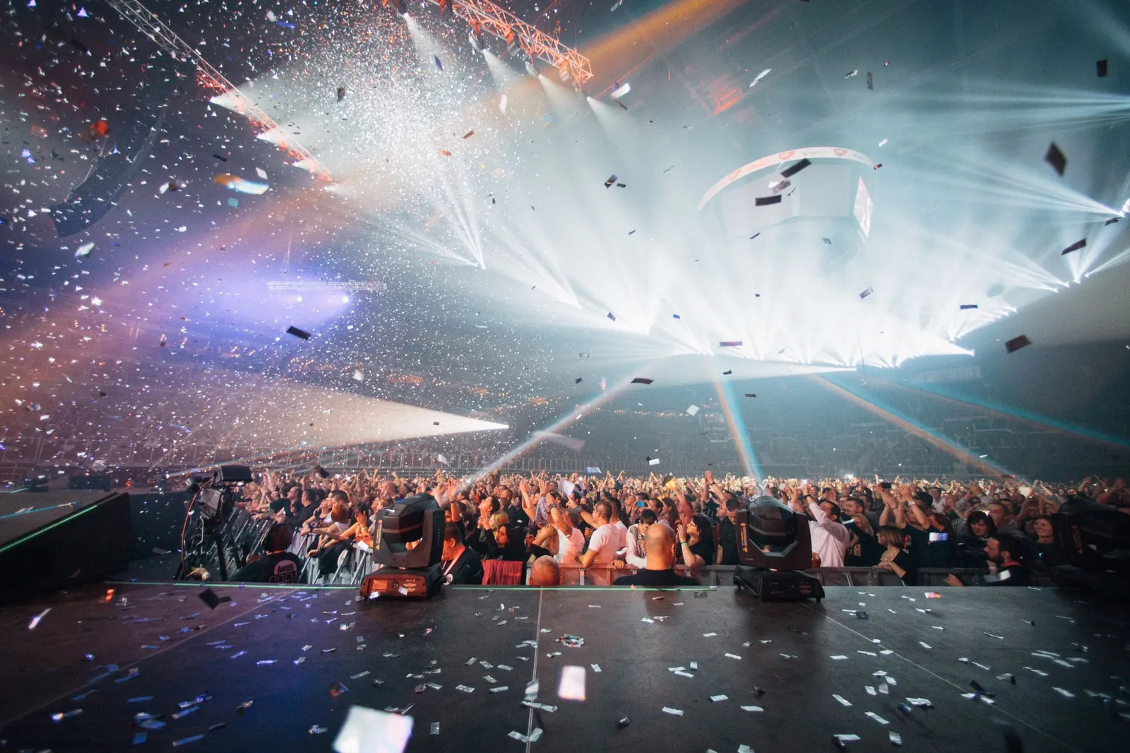 A packed esports arena crowd lit by stage lights during a live game event